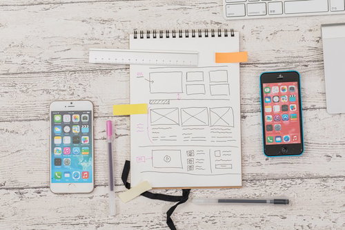 白いデスクに広げたスマホと手書きのデザインメモ