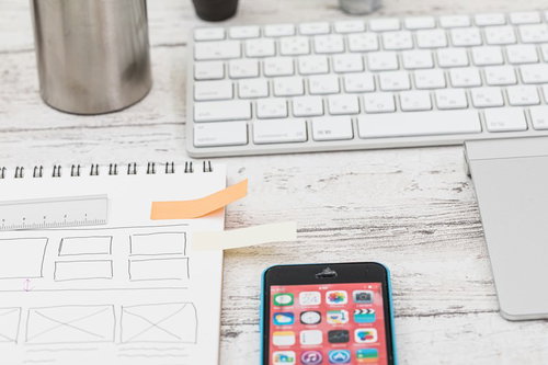 メモ用紙に貼られたオレンジ色の付箋紙とスマートフォン