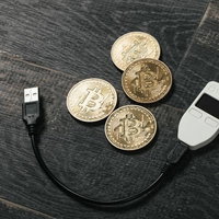 フローリングに置かれたビットコインとビットコインウォレット（TREZOR)の写真