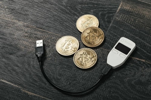 フローリングに置かれたビットコインとビットコインウォレット（TREZOR)
