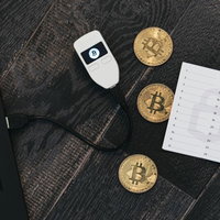 散らばるビットコインと資産管理するハードウェアウォレットの写真