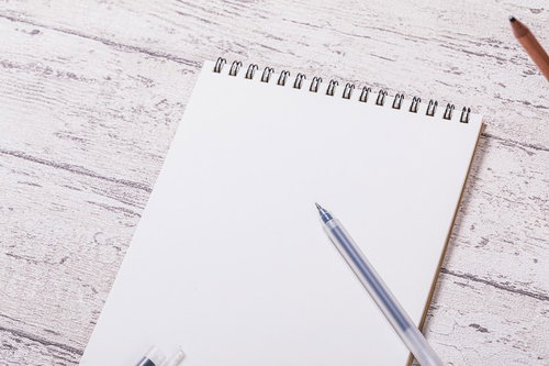 白紙のリング式メモ帳とシルバーのボールペン