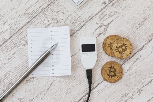 メモ書きと並べたTREZORとビットコイン