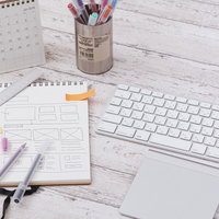 付箋付きのメモ用紙とキーボード、定規やペンなどの文具が並ぶデスクの写真