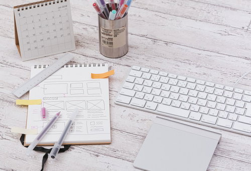 付箋付きのメモ用紙とキーボード、定規やペンなどの文具が並ぶデスク