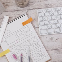 スクワーク中のノートとキーボード、文具が並べられたデスクの写真