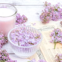 ライラックを盛った透明な器とキャンドルと楽譜の写真