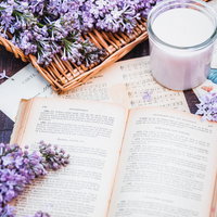 ラベンダーの生花とライラックが彩る洋書とキャンドルの写真