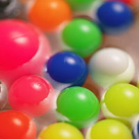 夏祭りの屋台で水面に浮かぶカラフルなスーパーボールの写真