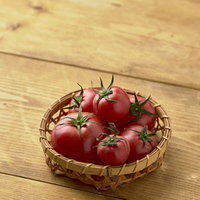 ヘタ付きミニトマトを詰めた藁籠、採れたて野菜の写真