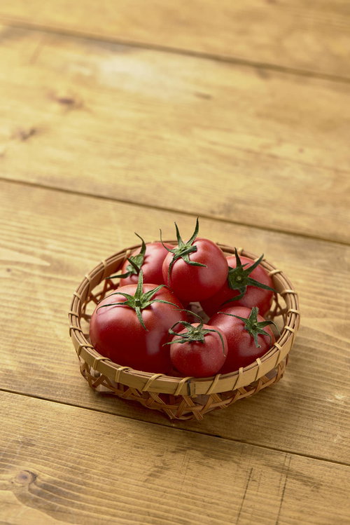 ヘタ付きミニトマトを詰めた藁籠、採れたて野菜