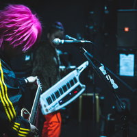 ライブ中にチューニングする派手髪のギタリストの写真