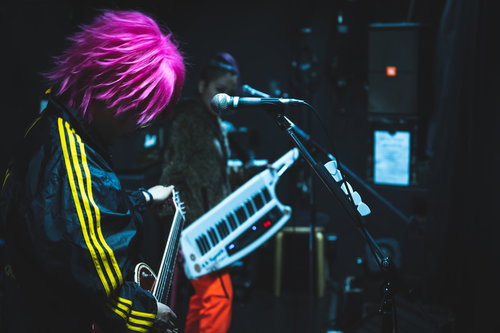 ライブ中にチューニングする派手髪のギタリスト