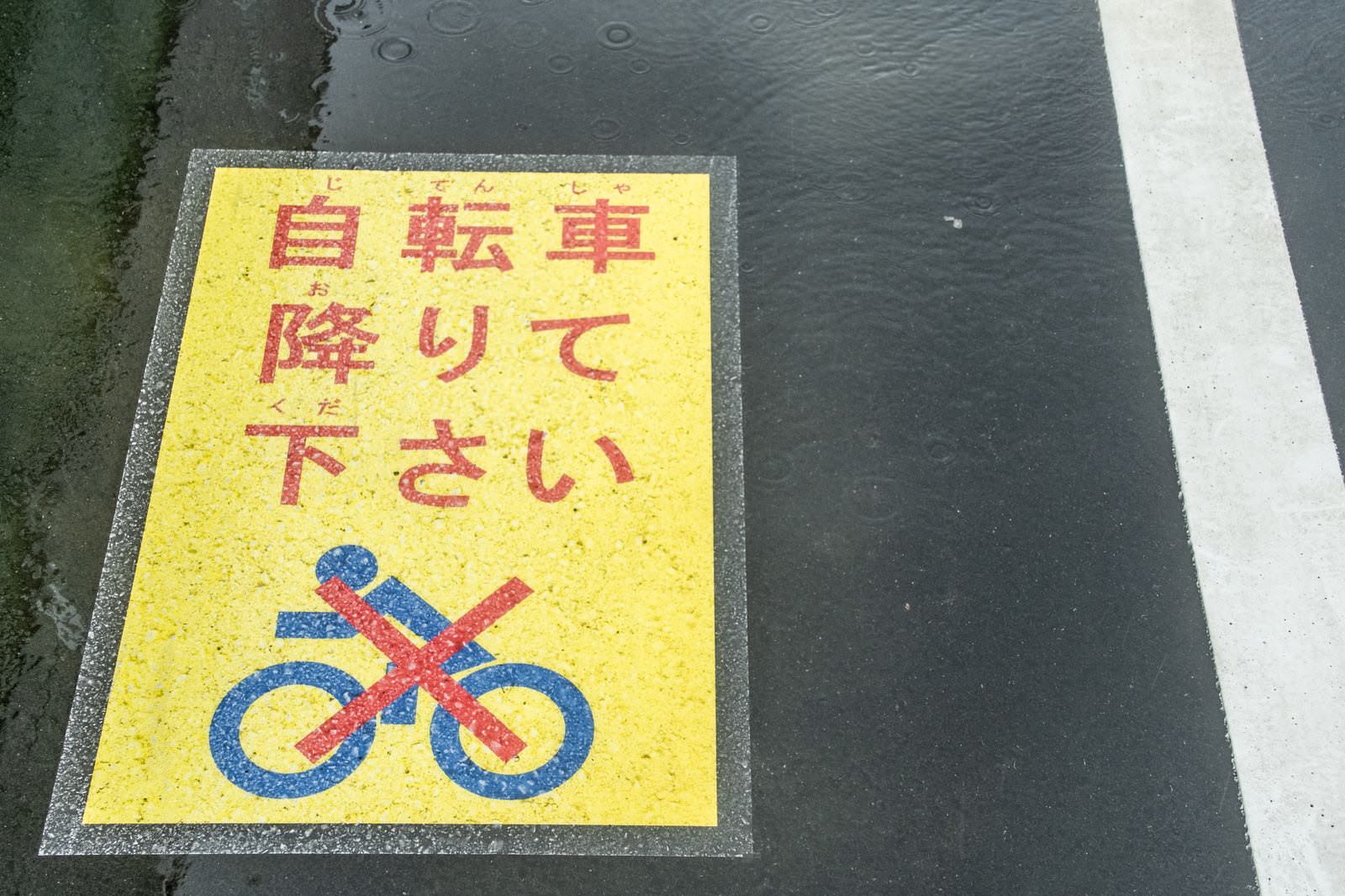 歩道に設置された黄色い自転車降車を促す注意喚起看板