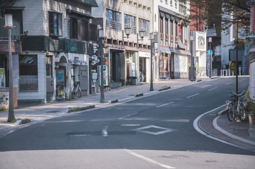 愛媛県の商店街、路面店と車道が続く晴天の坂道