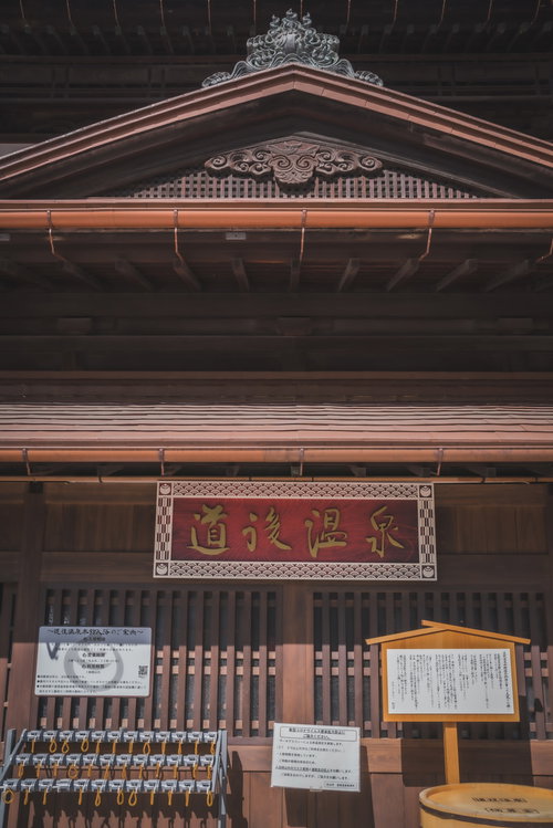 道後温泉の老舗店頭に掲げられた赤い看板と格子戸