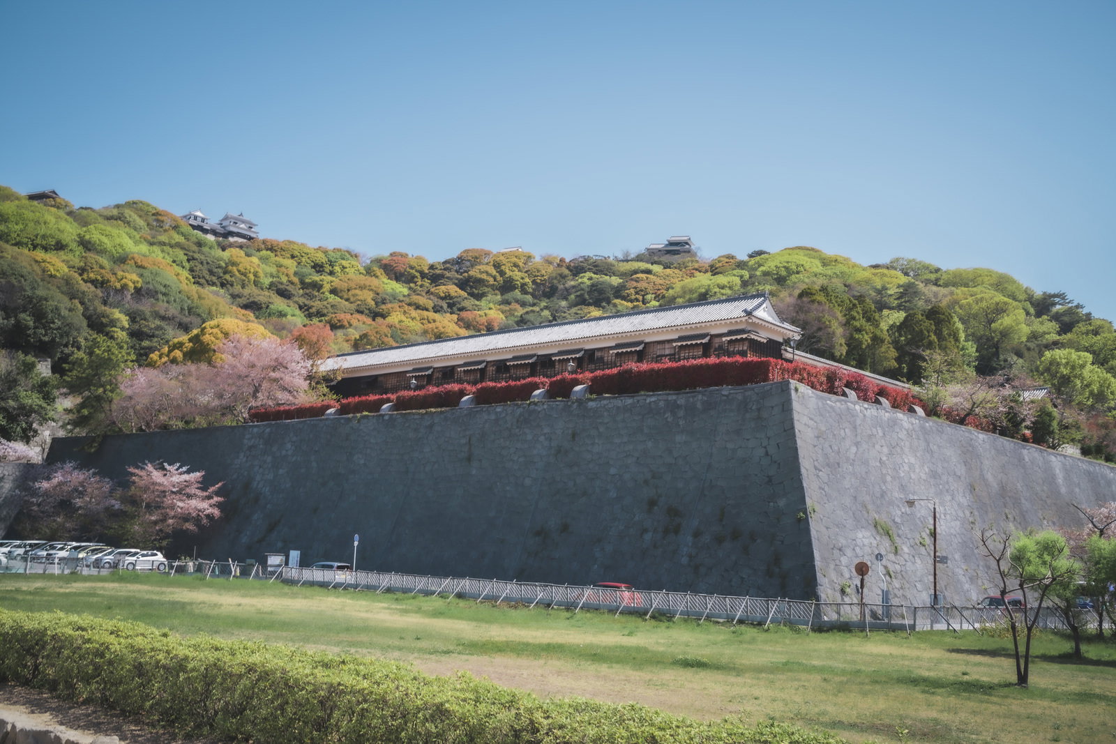 石垣の上に建つ瓦屋根の櫓と秋の紅葉に囲まれた城跡