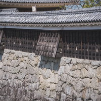 松山城の石垣上に構える重厚な土塀と狭間、瓦葺き屋根の写真