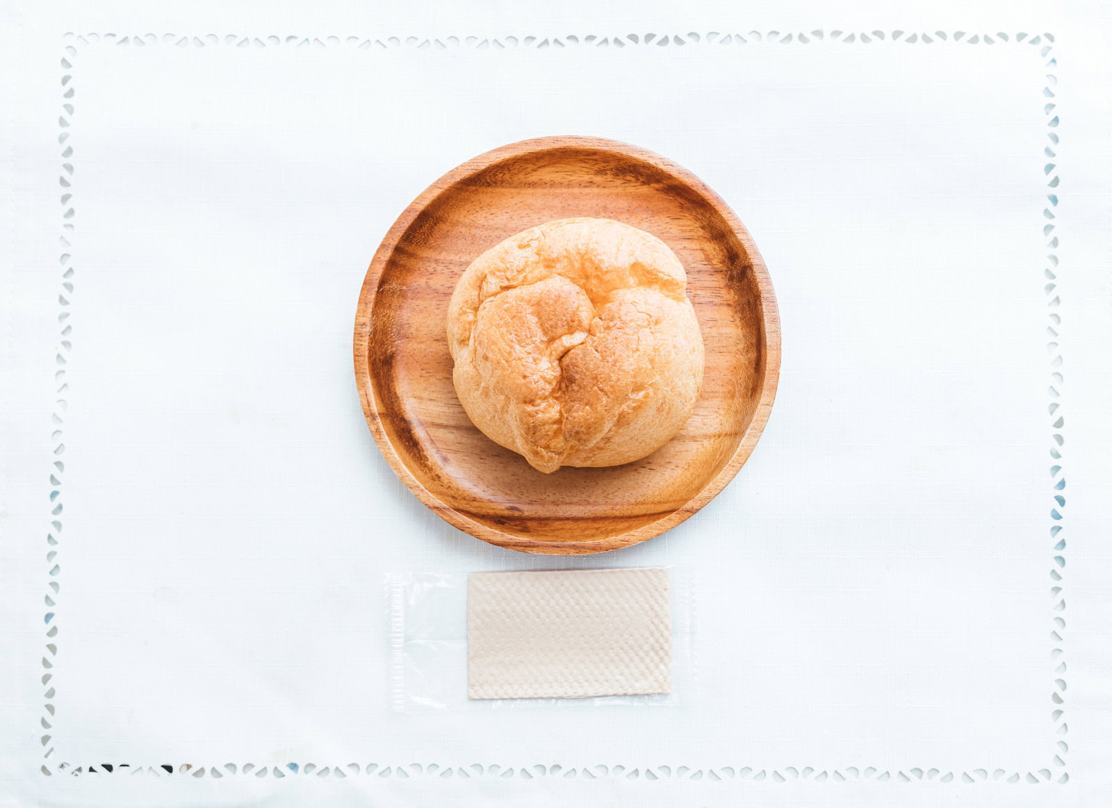 Cream puffs placed on a wooden plate against a white background