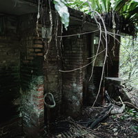 半壊した炭鉱住宅跡地の建物に残る小便器の写真