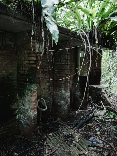 半壊した炭鉱住宅跡地の建物に残る小便器