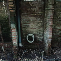 炭鉱跡地に残る苔むした小便器と崩落する男子便所の写真