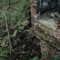 廃墟と化した炭鉱住宅の半壊した煉瓦の壁と便器の写真