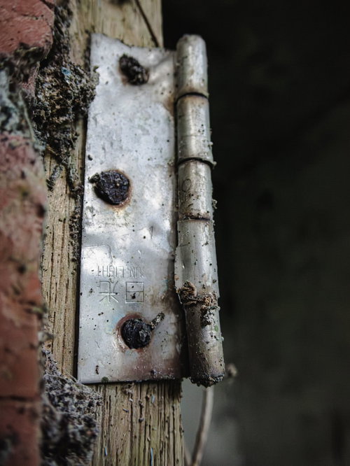 錆び付いた丁番と木製枠の劣化した金属ハードウェア