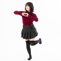 赤いセーターで両手でハートを作る女性の笑顔の写真