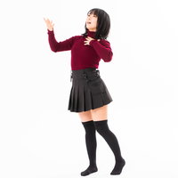 赤いセーター姿で胸に手をやり堂々とした態度の女性の写真