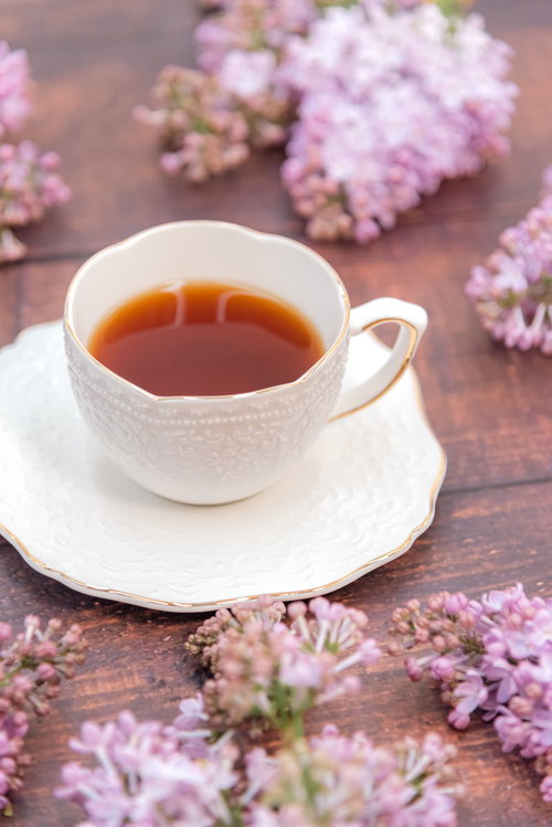 ティーカップのハーブティーとライラックの春の一杯