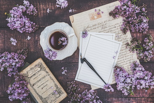 デスクに散らばるライラックとレターセット、コーヒーカップ