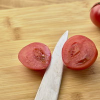 木製まな板の上でカットしたミニトマトの断面の写真