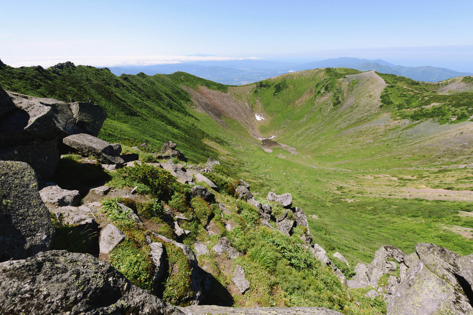 羊蹄山山頂から見た父釜火口の風景、緑の草原と岩壁