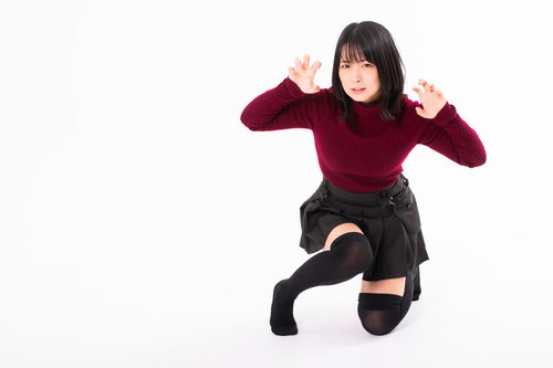 物陰に隠れて膝立ちで驚かそうとするガォーポージングの女性