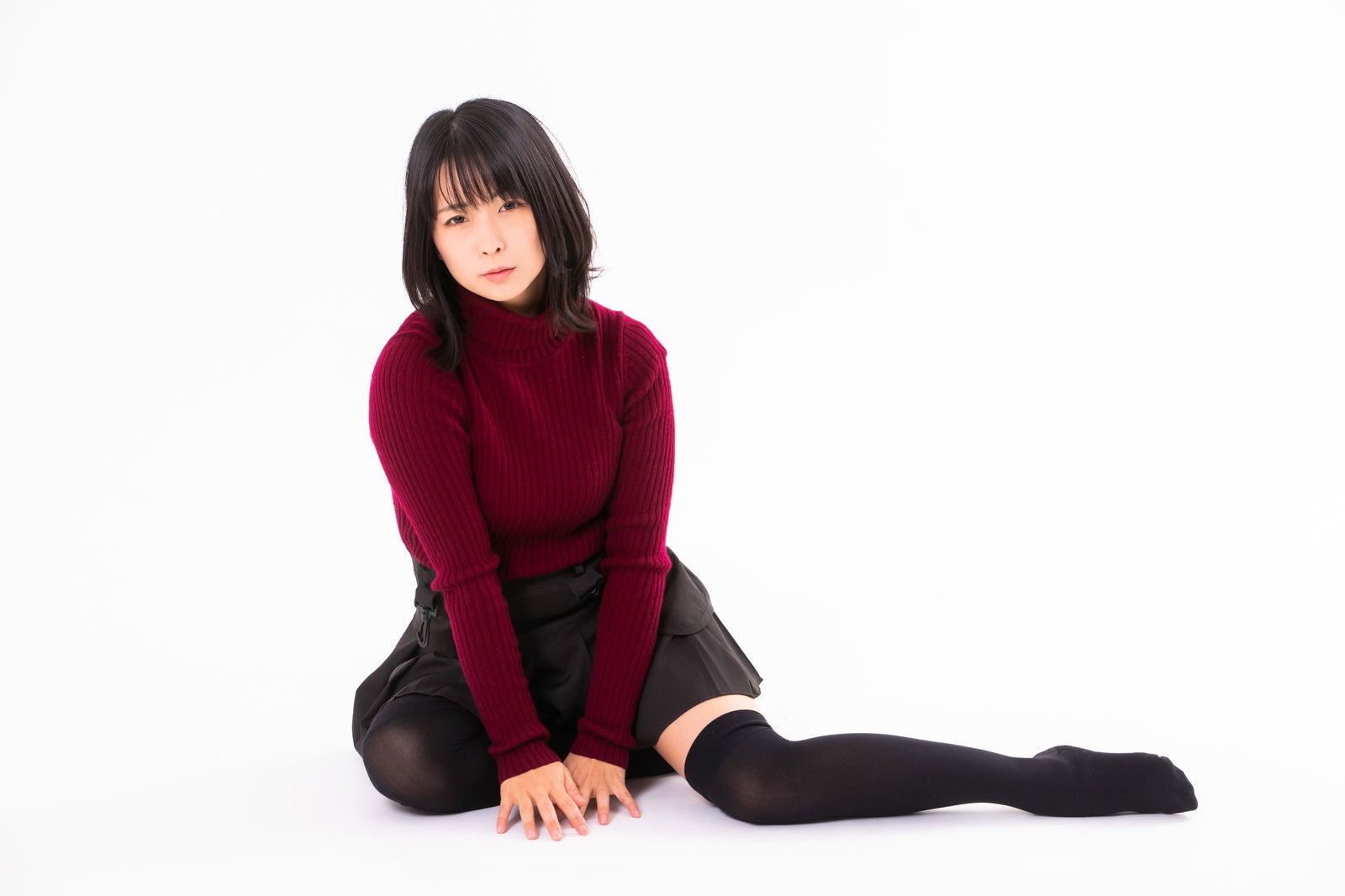ボルドー色のニットを着た女性が横座りで片足を伸ばしているポーズ［モデル：にゃるる］