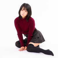 赤いニットセーターを着て床に座り込む女性の写真