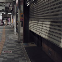開店を待つ駅前の商店のシャッターと朝の歩道の風景の写真