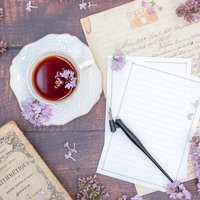 ライラックが添えられた便箋と万年筆、紅茶のティータイムの写真