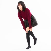 ハイソックスを引っ張り上げる赤いトップスの女性の写真