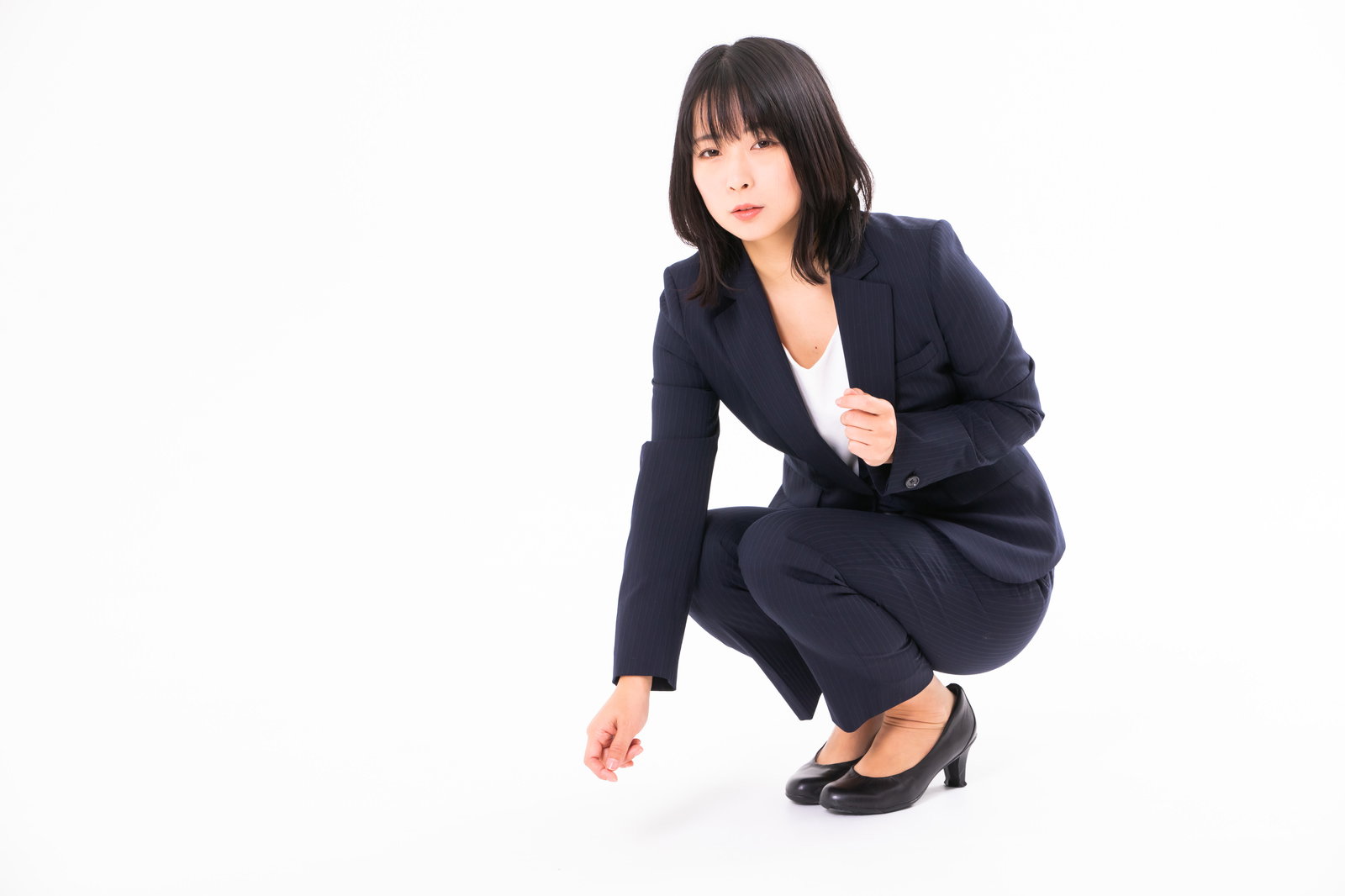 黒いスーツを着た女性がしゃがんでいる様子［モデル：にゃるる］