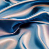 柔らかく波打ちながら光を反射するブルーのサテン生地の写真