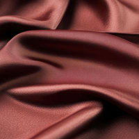 深みのある赤茶色のサテン生地にできた波状のドレープの写真