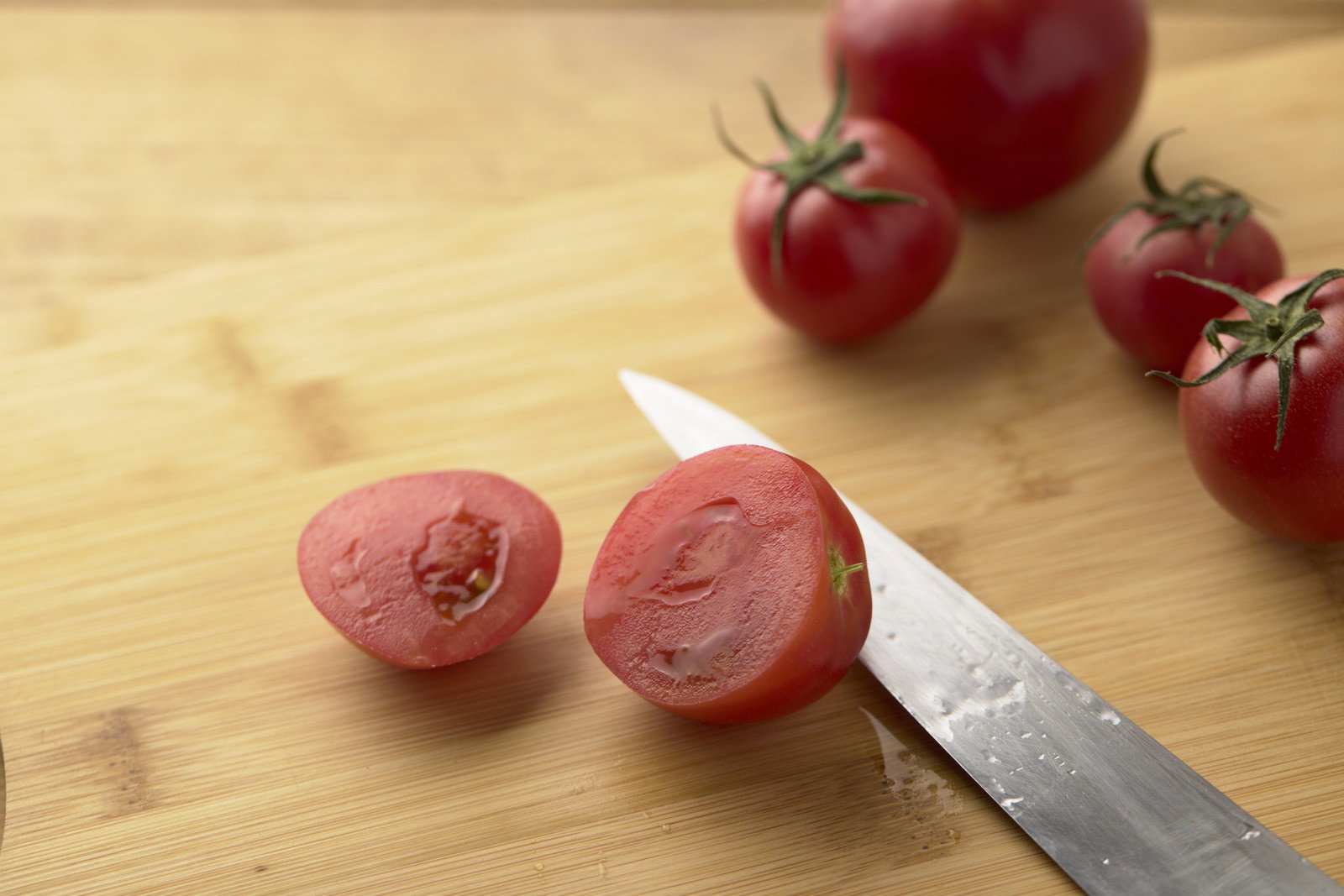 Cross-section of cherry tomatoes cut on a cutting board with a knife