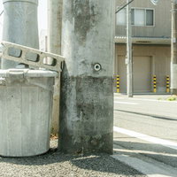 住宅街の道端に設置されたゴミ箱とコンクリートブロックの写真