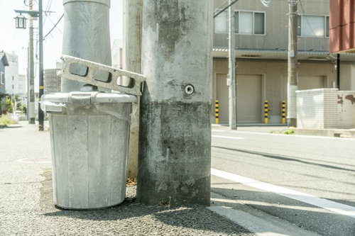 住宅街の道端に設置されたゴミ箱とコンクリートブロック