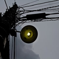 暗い曇り空を背景に立つ古い電灯のシルエットの写真