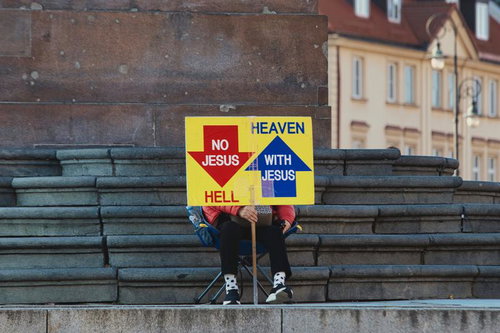 ワルシャワの石段に座りメッセージ性の強い看板を掲げる人物