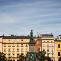 ポーランドのクラクフ中央市場広場に立つ銅像と歴史的建造物の写真