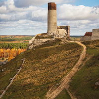 チェンストホバの古城跡と秋の丘陵風景、歴史的な石造りの塔の写真